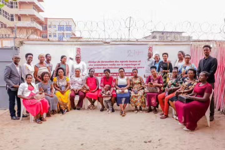 A group poses in front of a banner announcing the gender-sensitive reporting workshop from 29 to 31 July 2024.