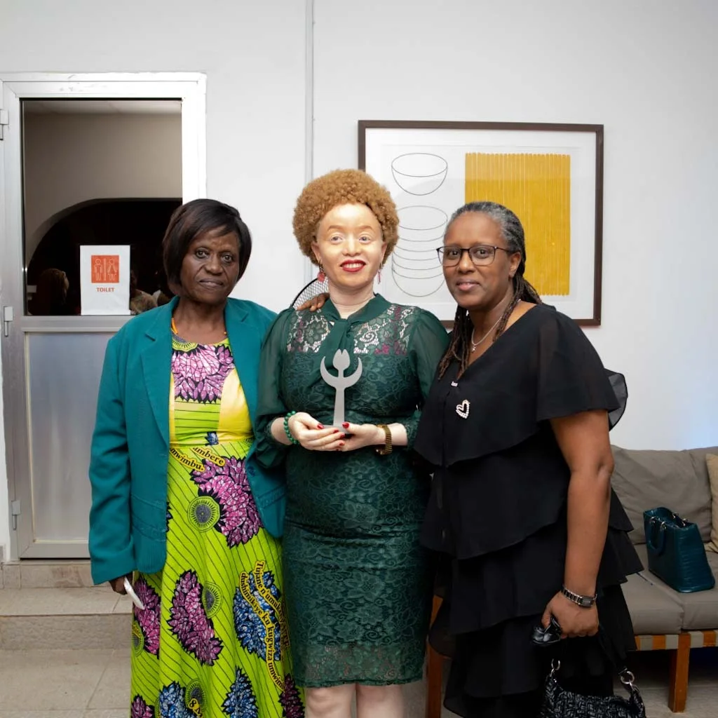 Three women stand side by side in a bright hall, facing the camera.