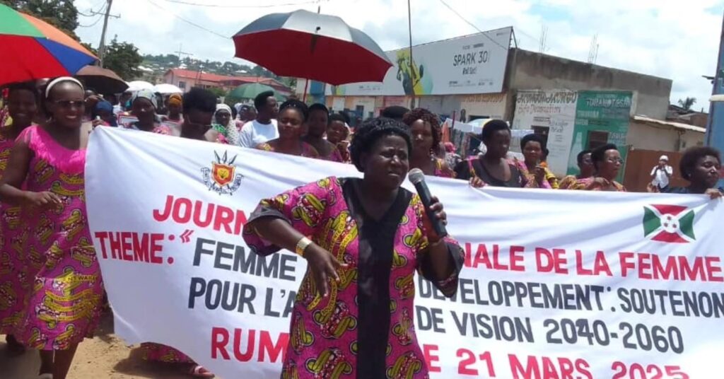 People hold a white banner reading “Journée internationale des droits des femmes” and “Rumonge, 21 Mars 2025.”