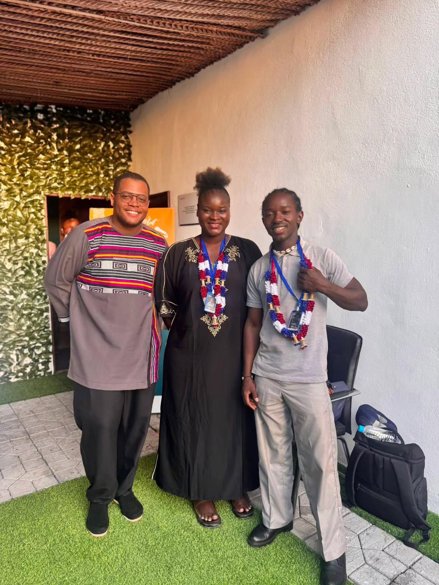 Four people pose together indoors, wearing event badges and lanyards.