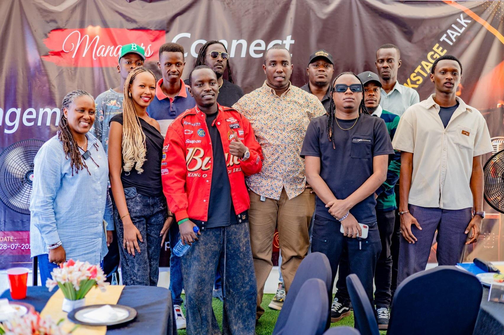 A group poses for a photograph in front of a Managers Connect banner.