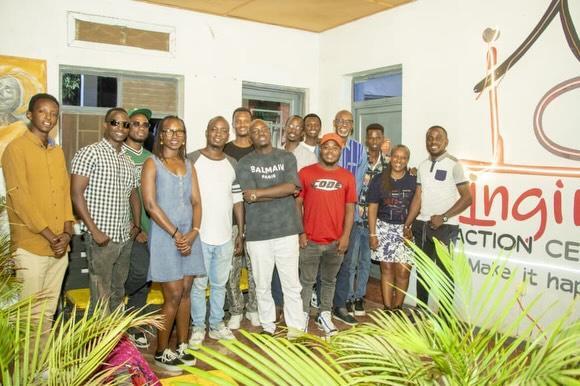 A group poses together indoors beside an Ingiro Action Center sign.