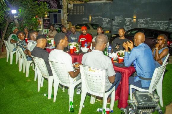 A group sits in chairs around a table outdoors at night.