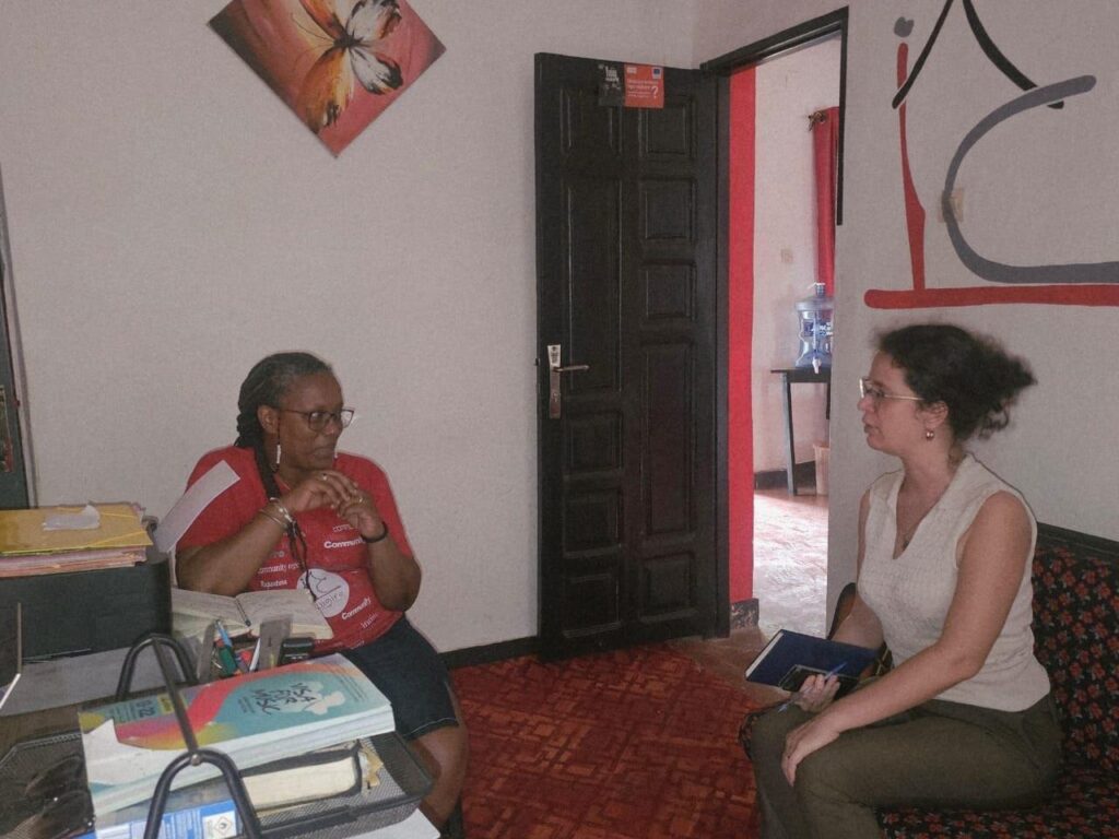 Two women sit facing each other in a small meeting room.