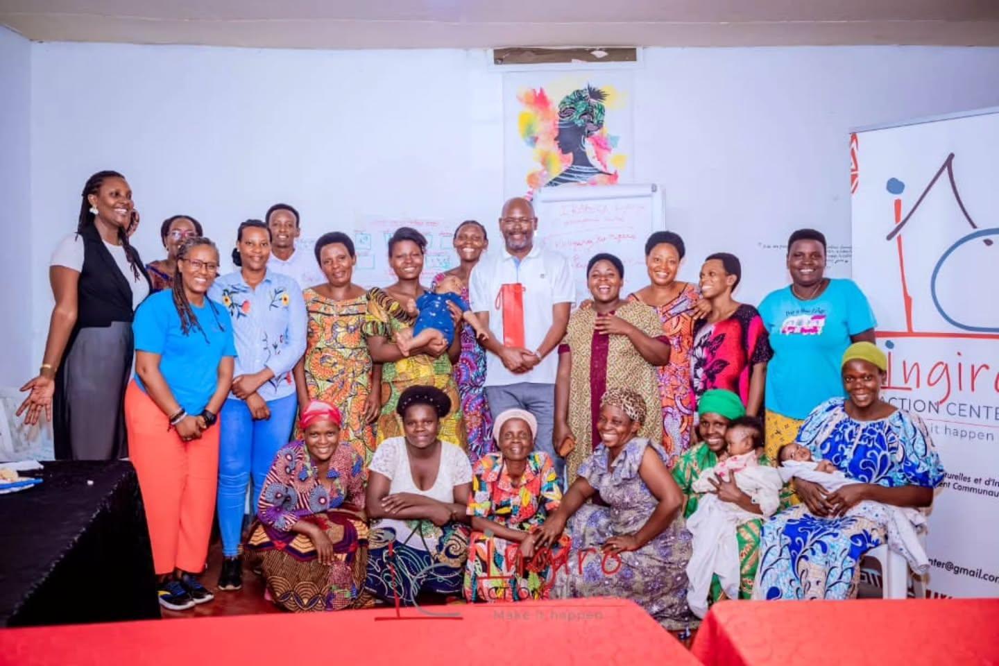 A large group poses inside a hall in front of an Ingiro Action Center banner.