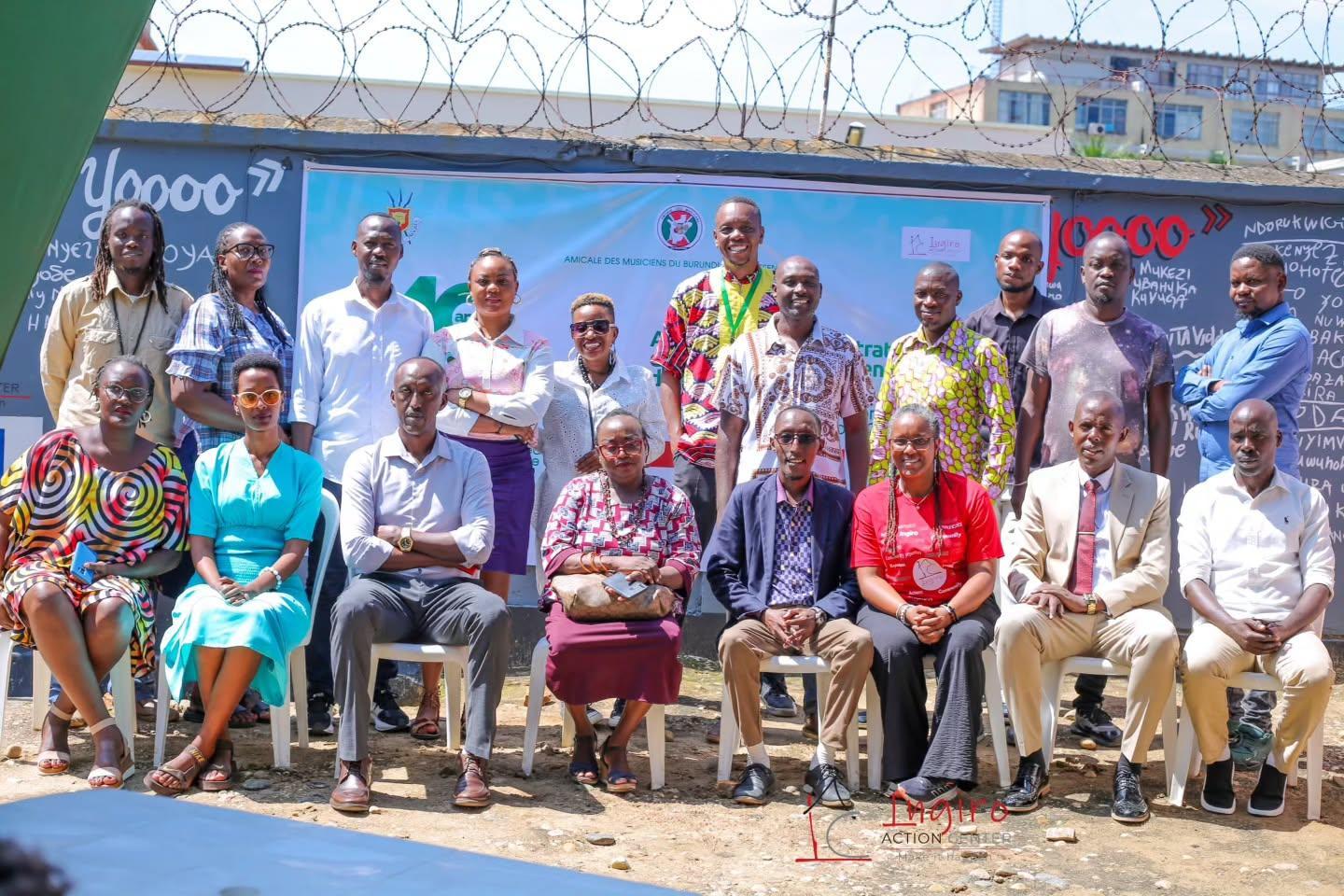 A large group poses in a hall with an Ingiro banner behind them.