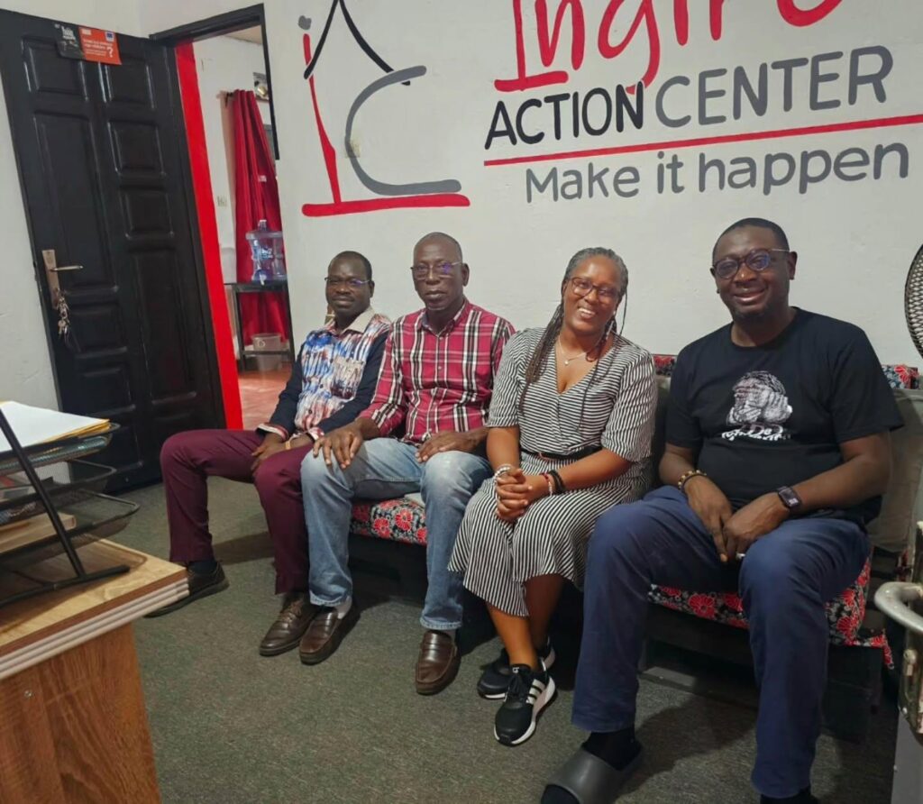 Four people sit together in an office with an Ingiro Action Center sign behind them.
