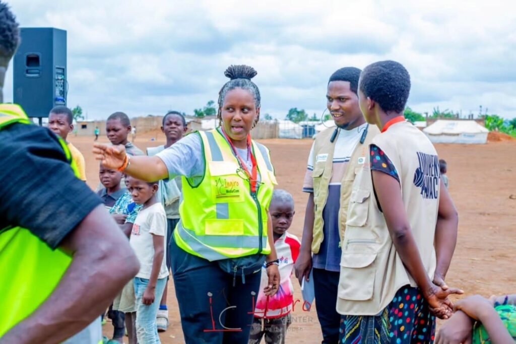 Several people in reflective vests stand together outdoors near a vehicle.