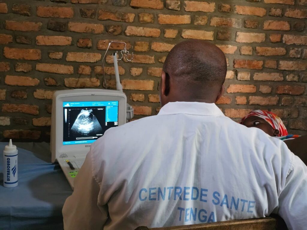 A doctor in a white coat looks at an ultrasound screen.