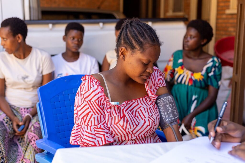 A pregnant woman has her blood pressure measured while another person writes on a form.