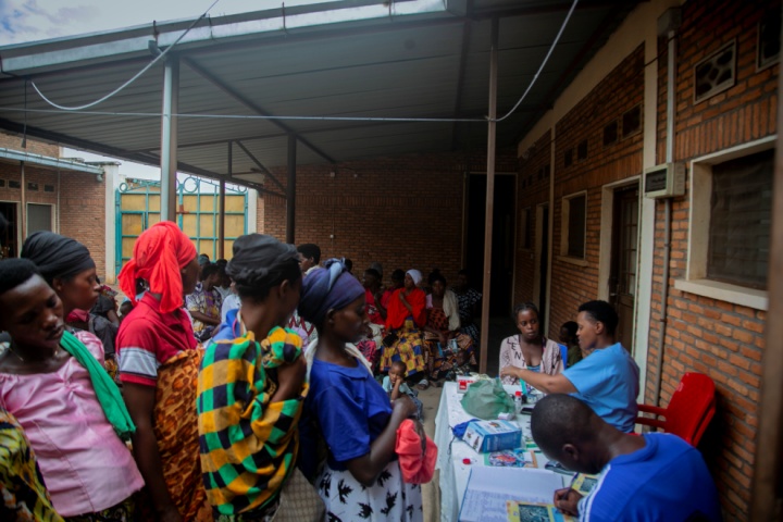 Les femmes font la queue dans une cour couverte à côté d'une table où les travailleurs de la santé enregistrent l'information.